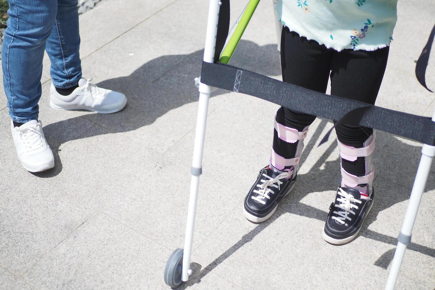 child with walking frame and knee orthosis outdoor photo