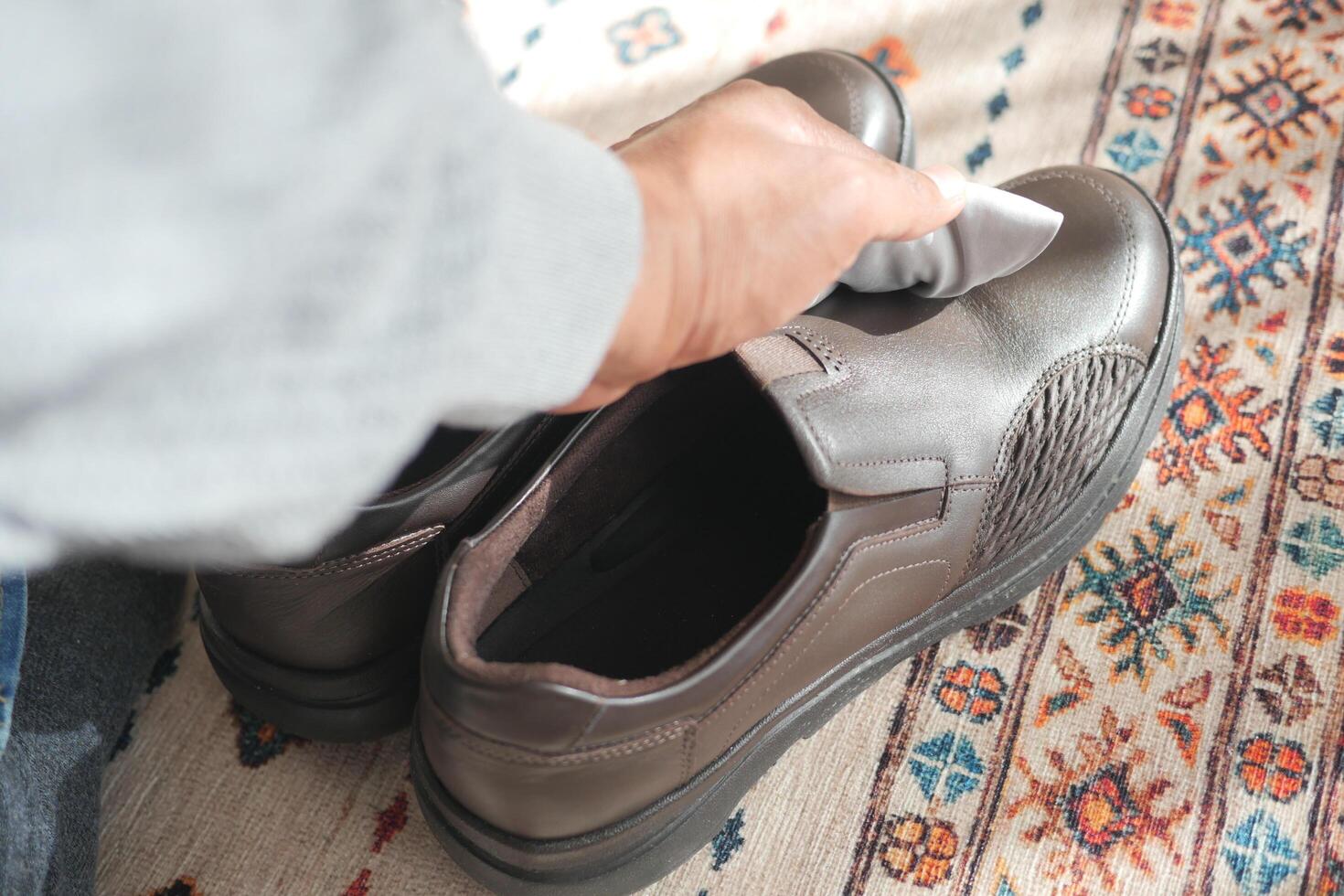 man wipes his leather shoes with a wet cloth photo