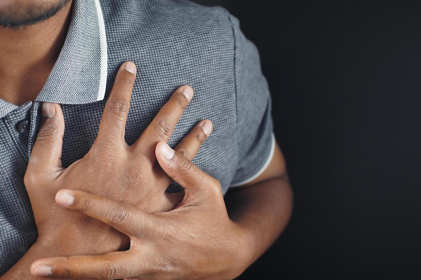 young man suffering pain in heart and holding chest with hand photo
