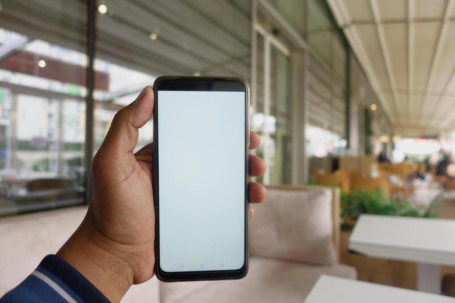 young man hand using smart phone with white screen at cafe photo