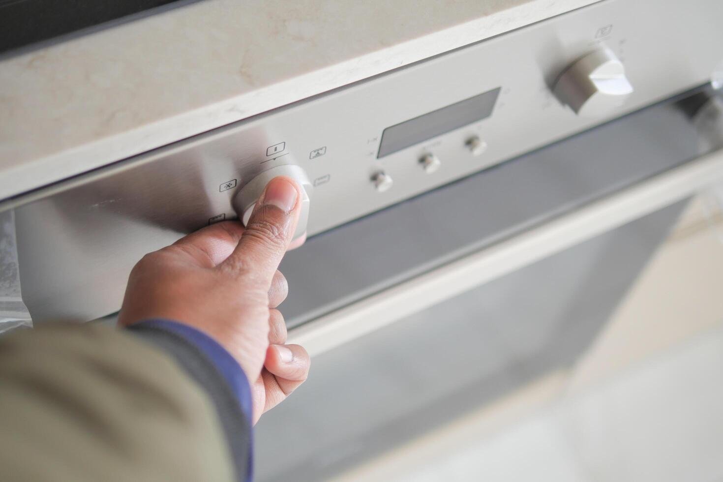 man hand setting temperature control on oven. photo