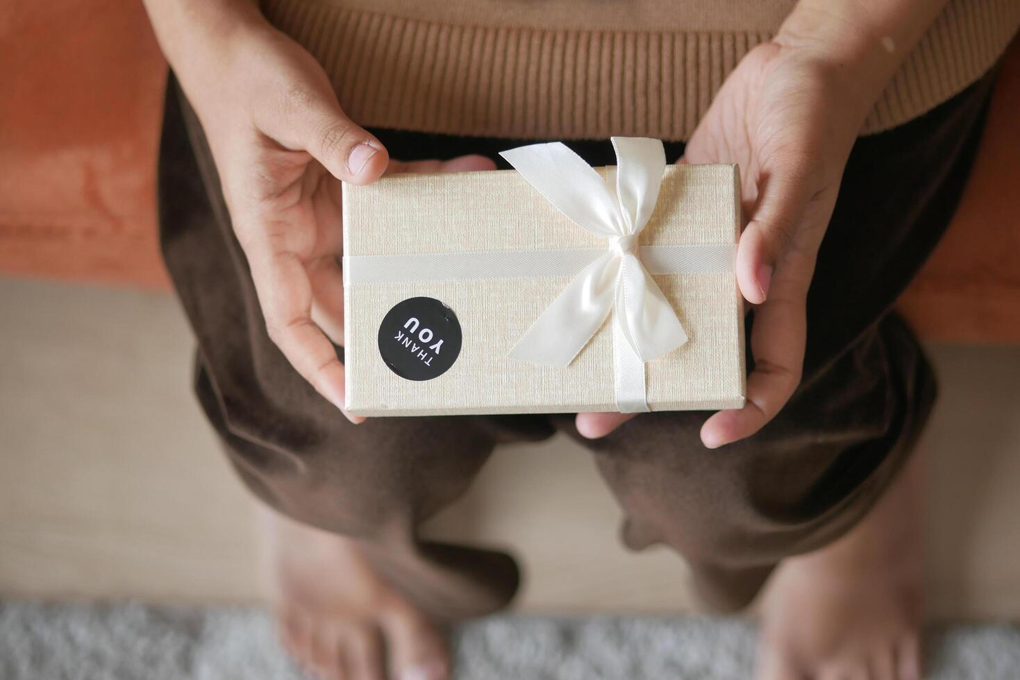 mano poniendo un gracias usted pegatina en un regalo caja foto