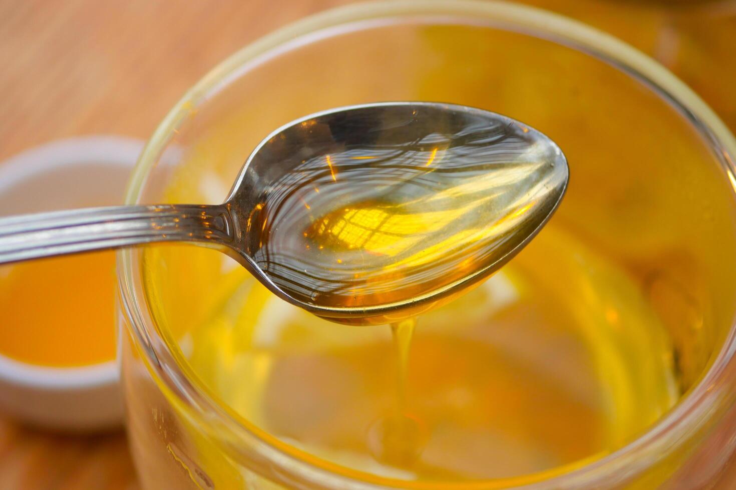 pouring honey in a cup of tea on table photo