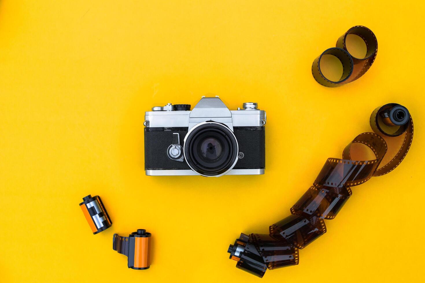 Flat lay vintage camera and film on yellow background photo