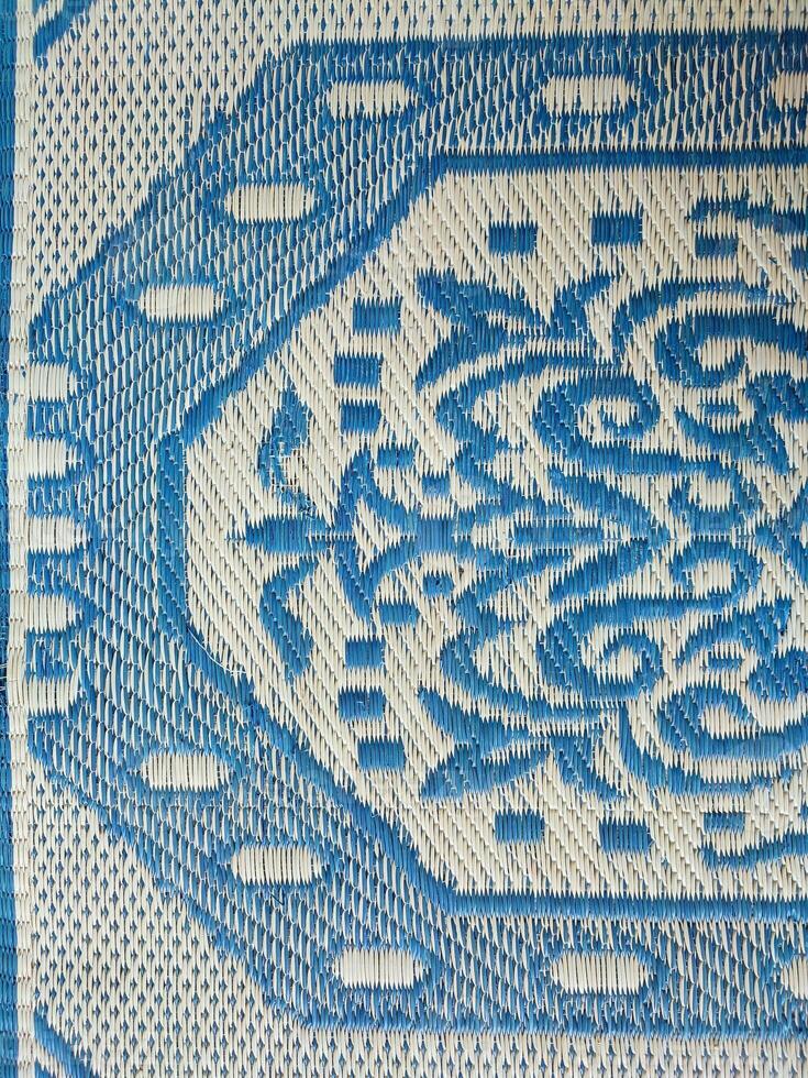 Blue and white woven mat with motif designs on it photo