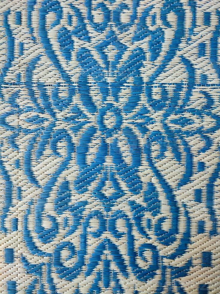 Blue and white woven mat with motif designs on it photo