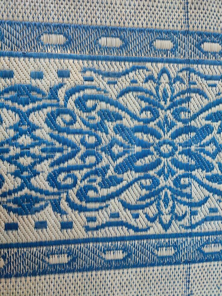 Blue and white woven mat with motif designs on it photo