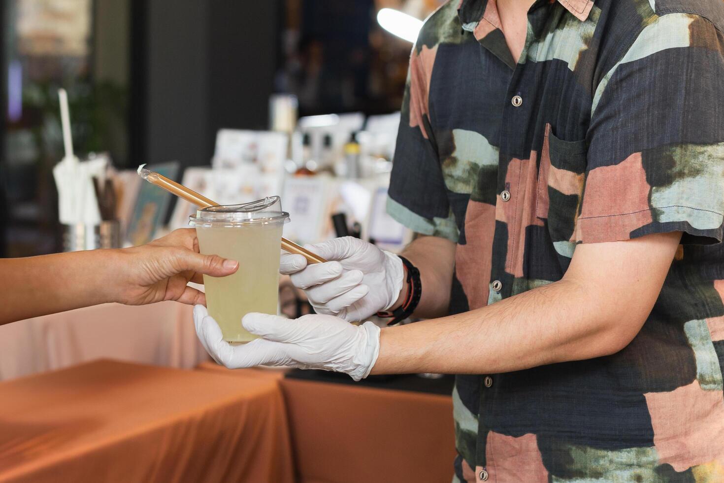 Man barista wearing groves serving drink to customer in cafe. photo