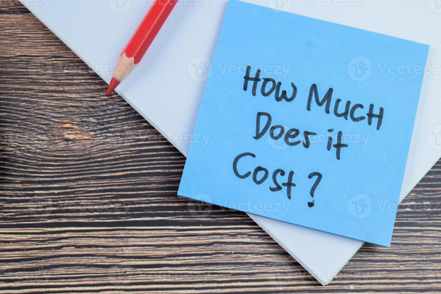 Concept of How Much Does it Cost write on sticky notes isolated on Wooden Table. photo