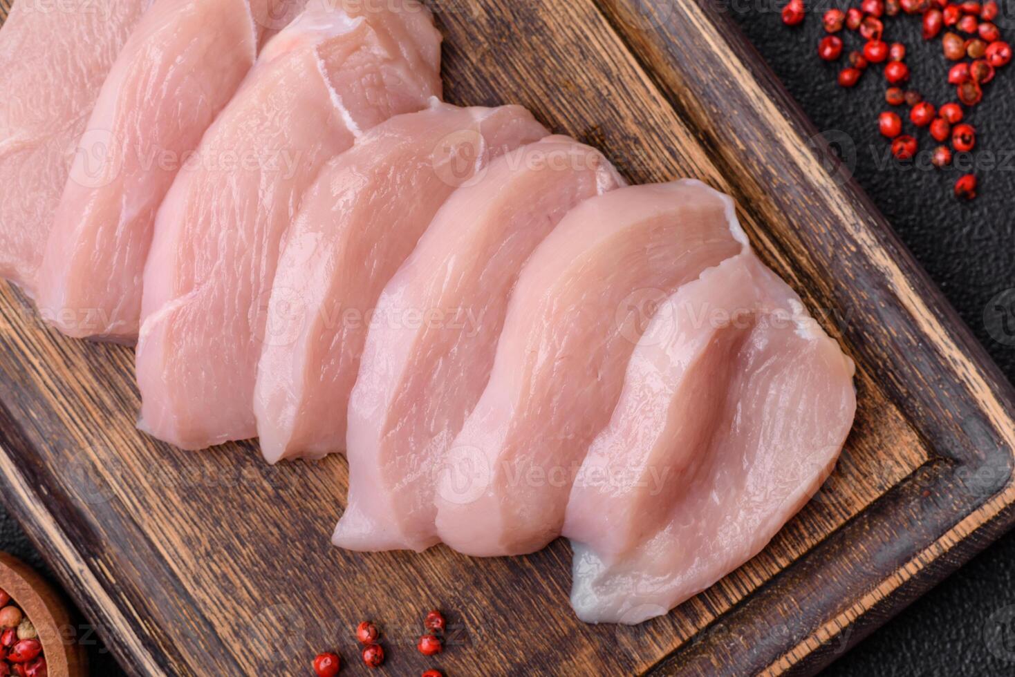 Slices of raw chicken or turkey fillet with salt, spices and herbs photo