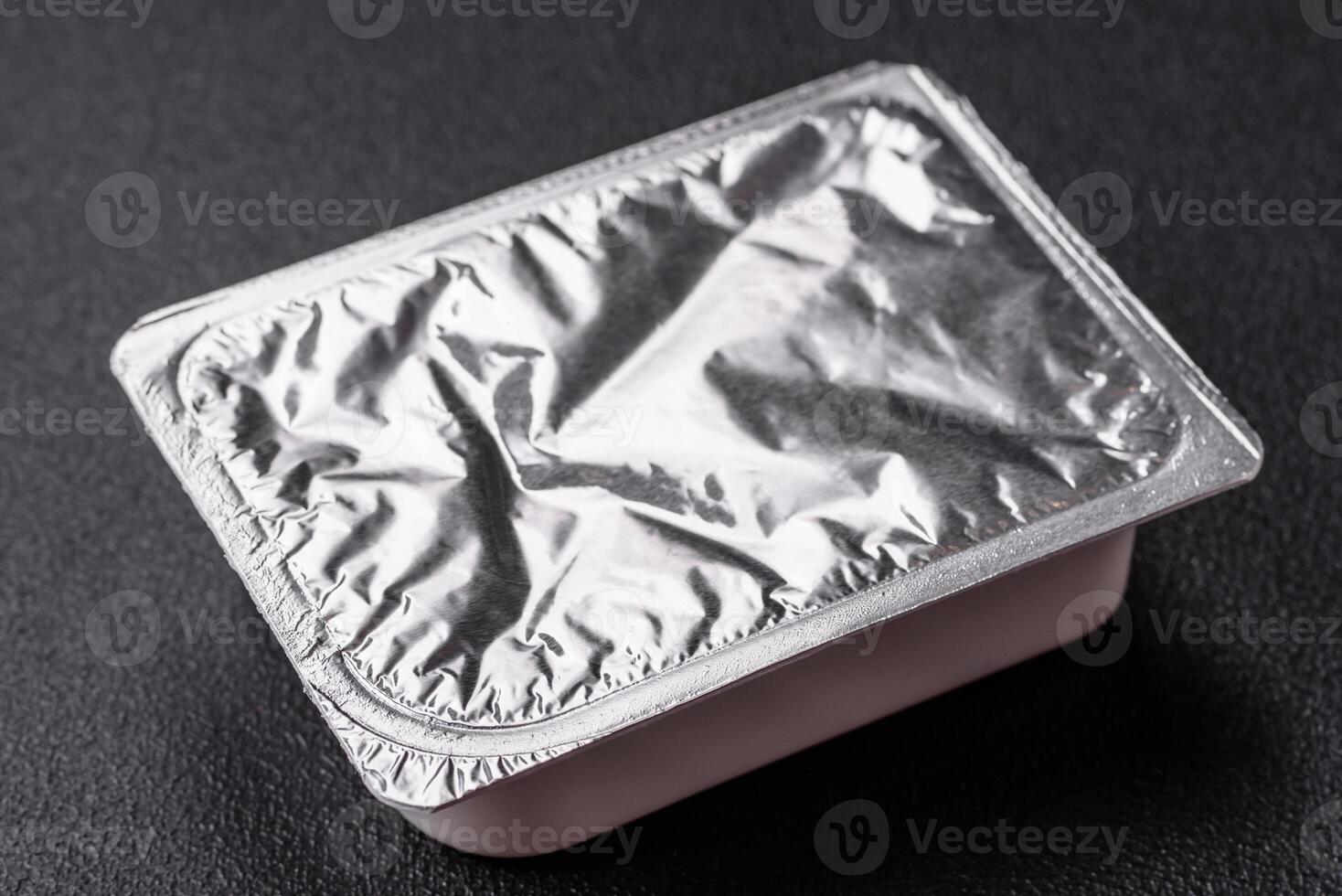 Rectangular plastic box with yogurt or cheese hermetically sealed with a foil lid photo