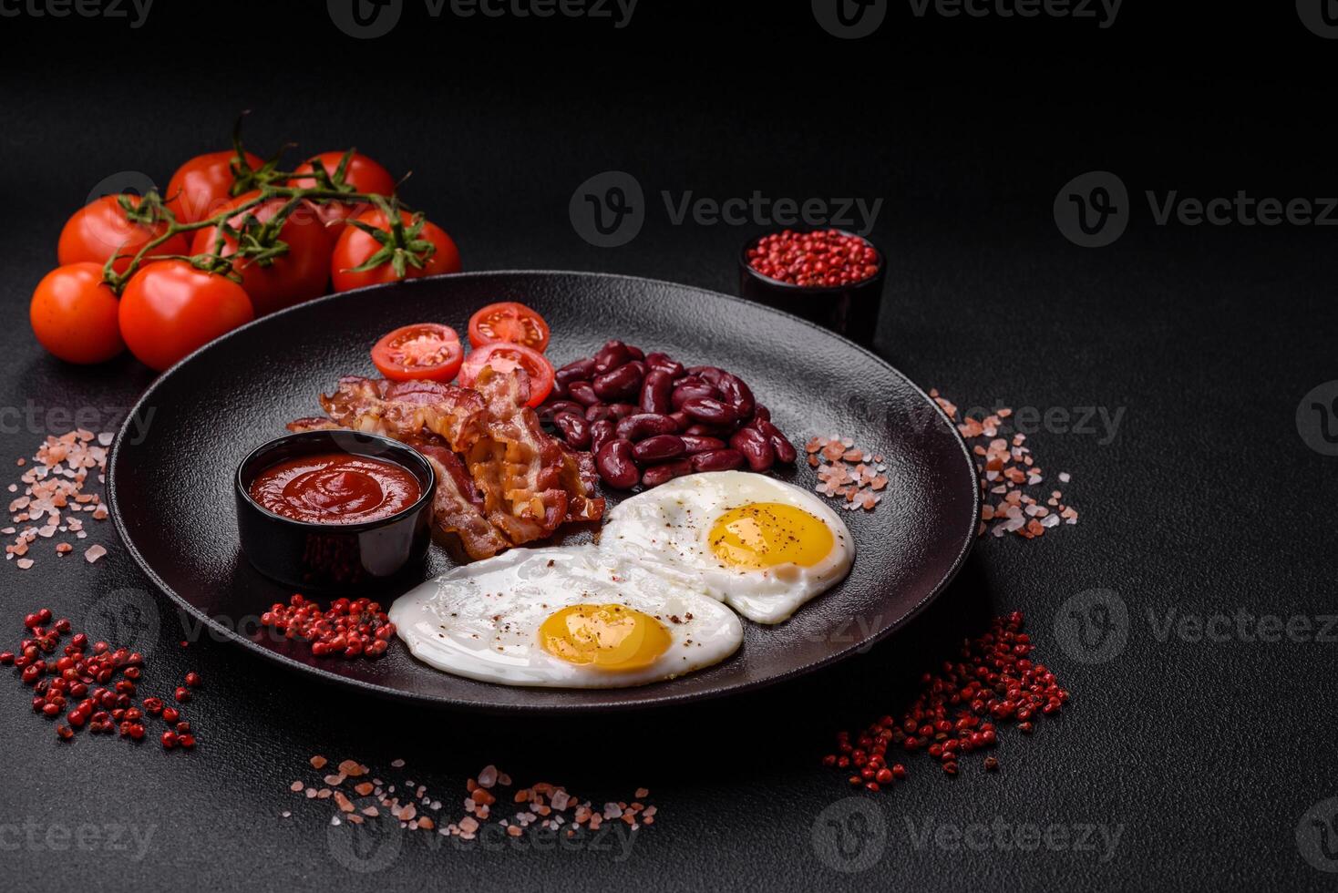 English breakfast with fried eggs, bacon, beans, tomatoes, spices and herbs photo