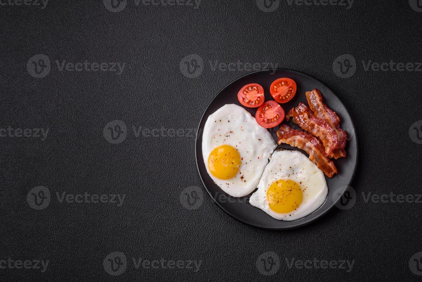 English breakfast with fried eggs, bacon, beans, tomatoes, spices and herbs photo