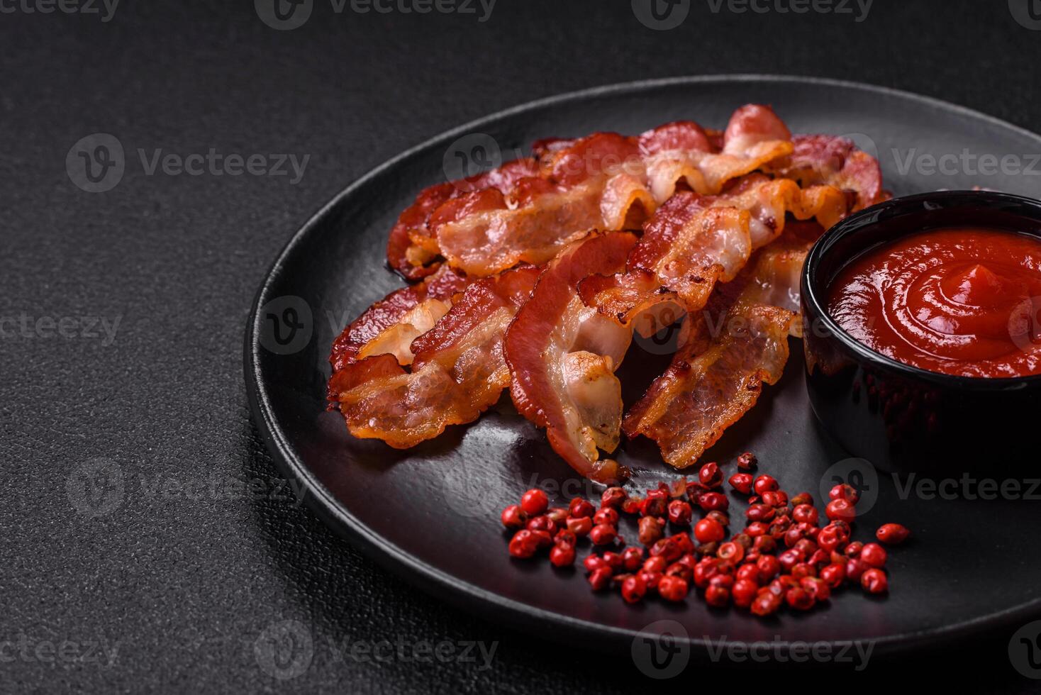 Delicious fresh fried bacon with salt and spices on a dark background photo