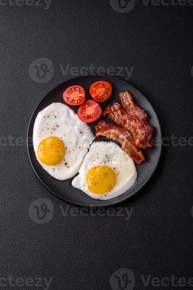 English breakfast with fried eggs, bacon, beans, tomatoes, spices and herbs photo