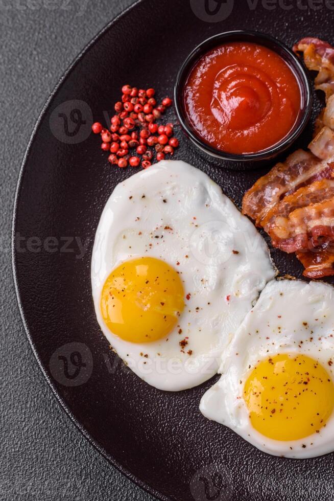 English breakfast with fried eggs, bacon, beans, tomatoes, spices and herbs photo