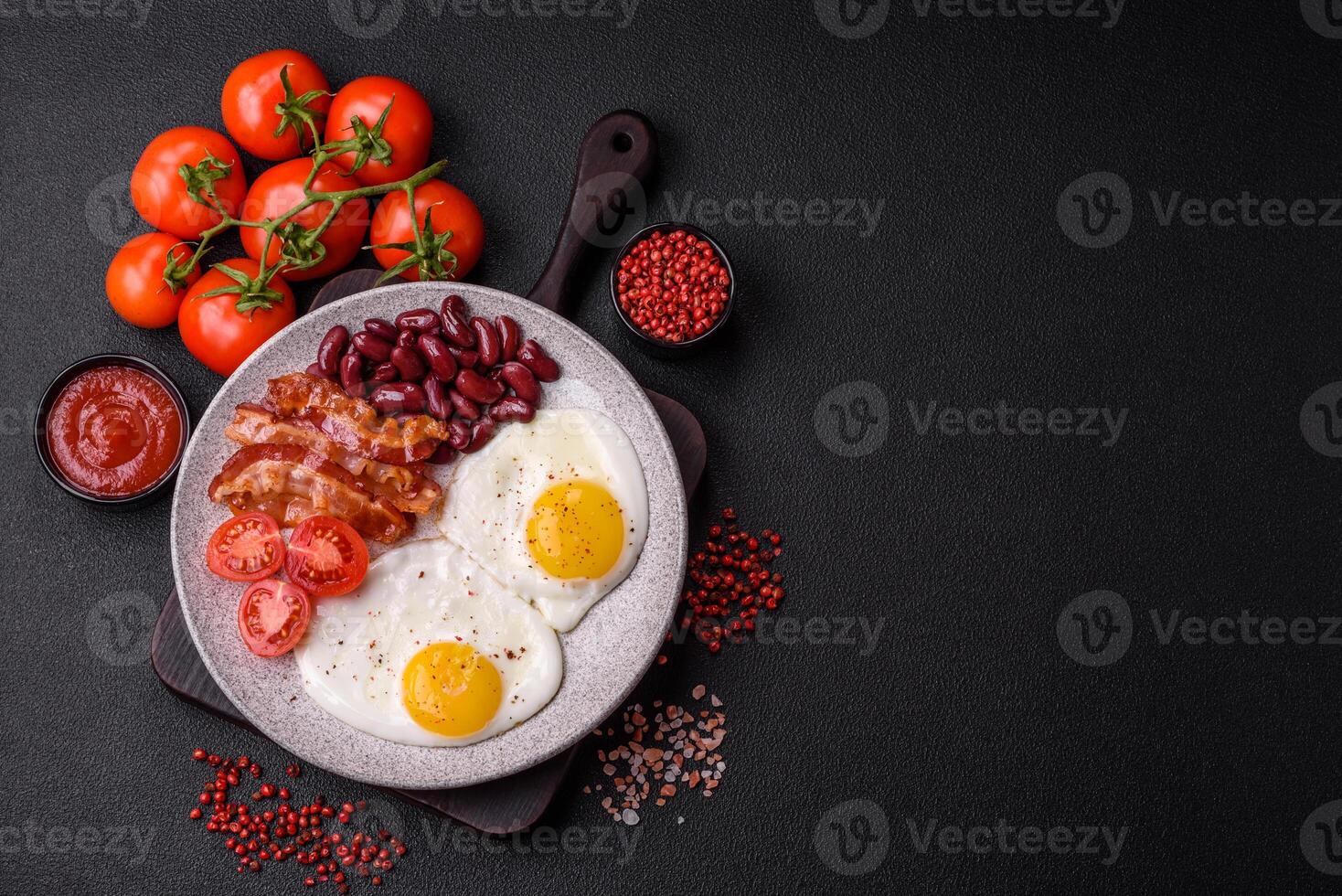 English breakfast with fried eggs, bacon, beans, tomatoes, spices and herbs photo
