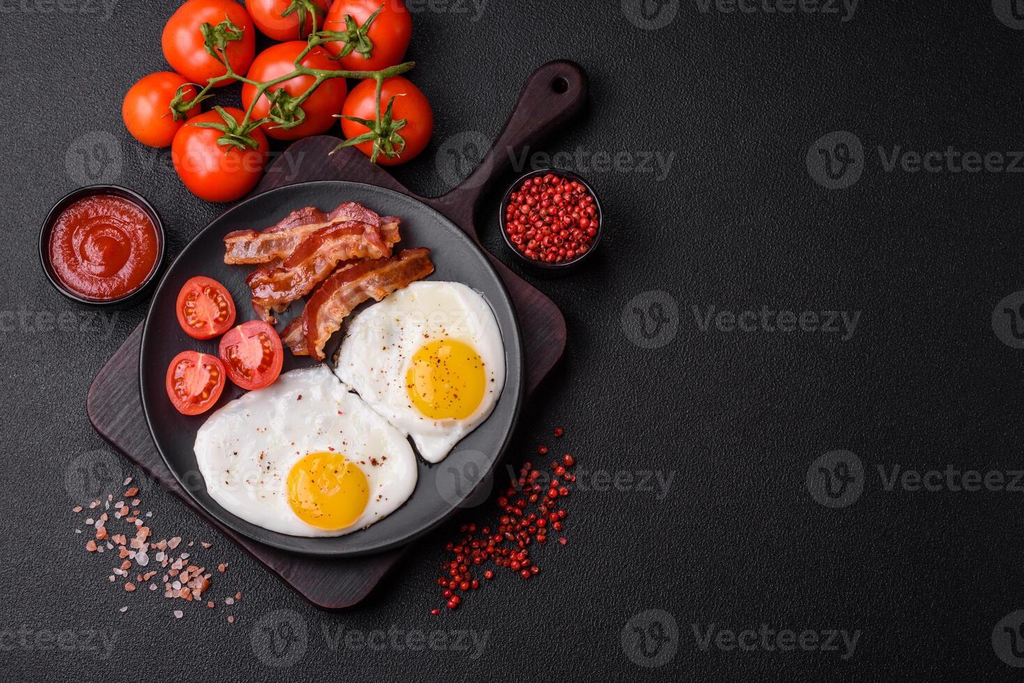 English breakfast with fried eggs, bacon, beans, tomatoes, spices and herbs photo