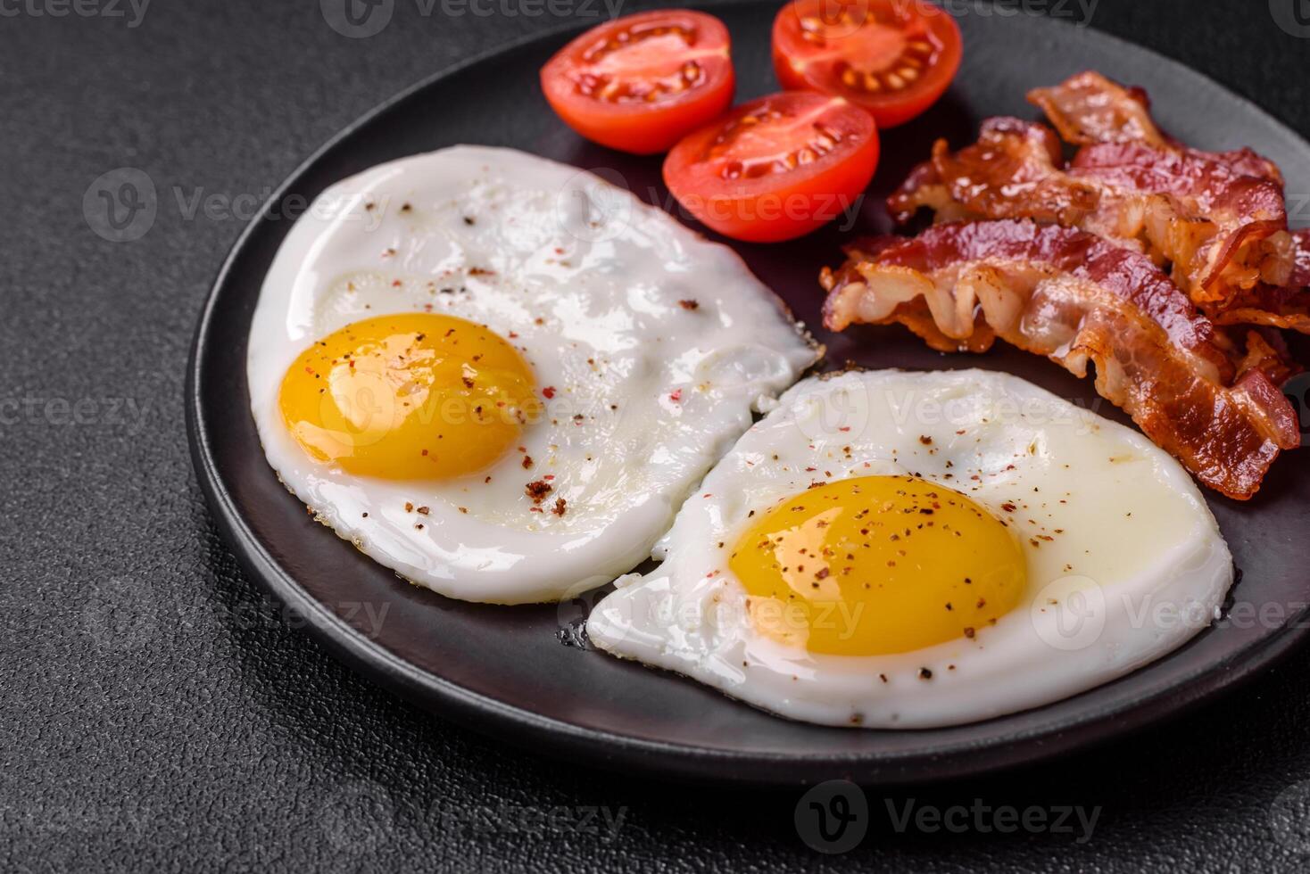 English breakfast with fried eggs, bacon, beans, tomatoes, spices and herbs photo