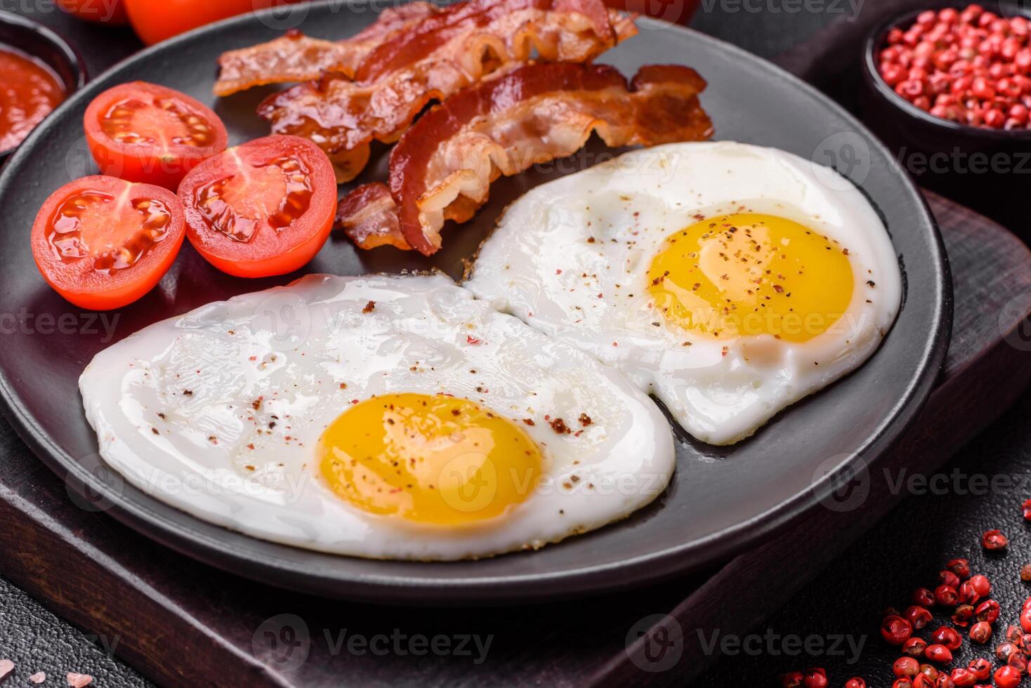 English breakfast with fried eggs, bacon, beans, tomatoes, spices and herbs photo