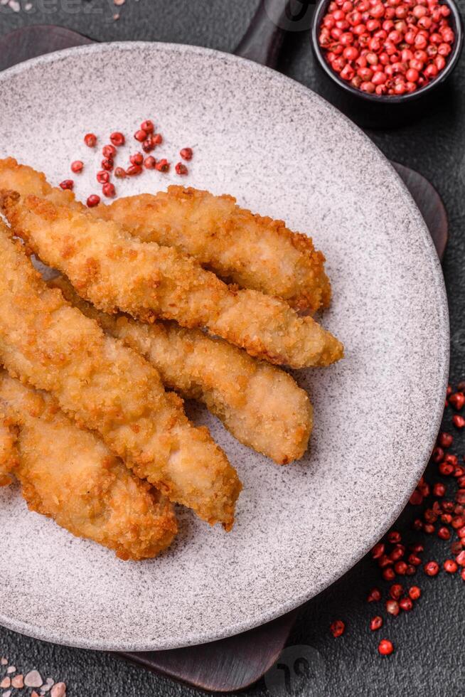 Delicious fresh chicken or turkey strips or nuggets breaded with salt and spices photo