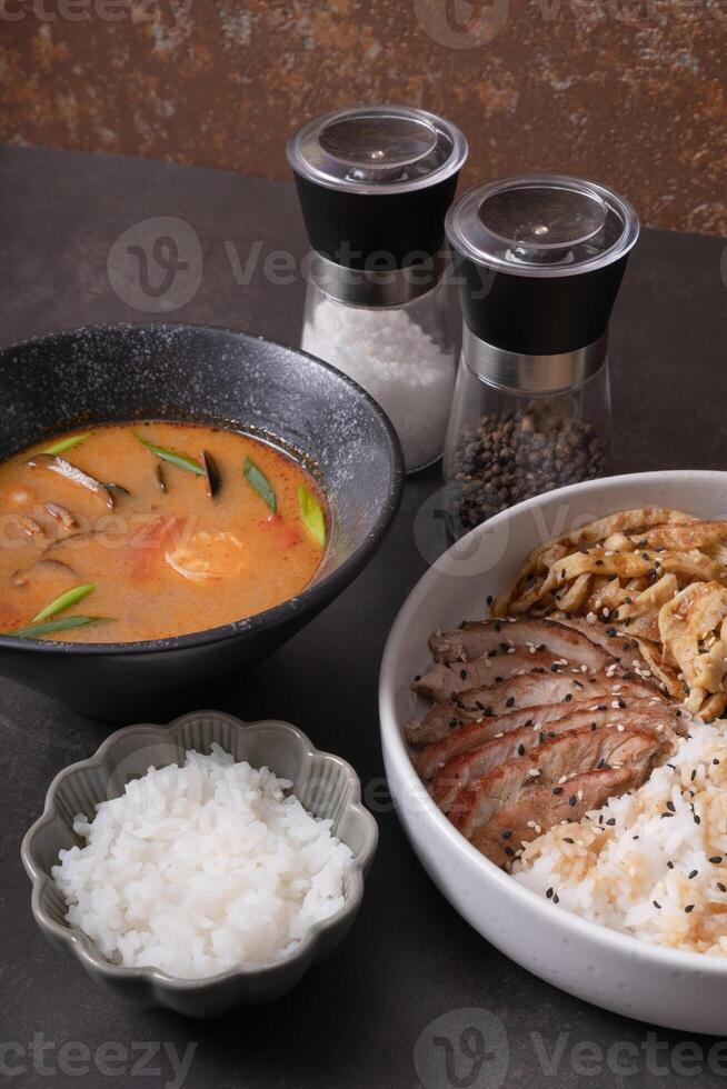 Tom yam soup and bowl with rice, veal and vegetables and angle view. photo