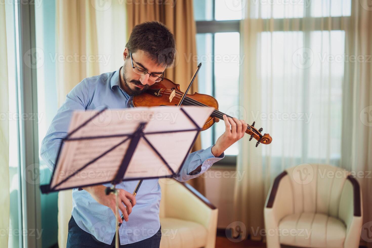 Man playing violin at home. He is practicing for live performance. photo