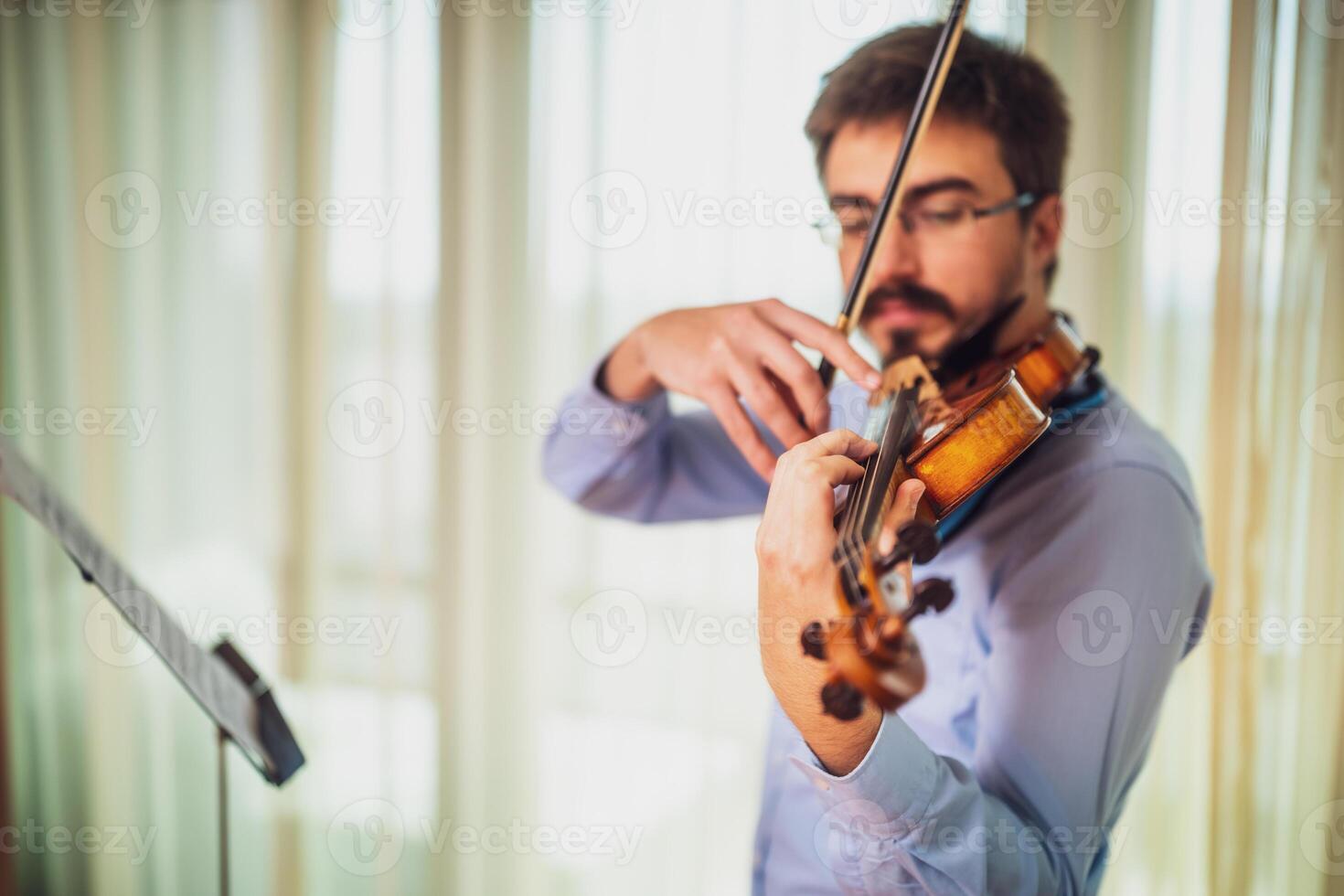 Man playing violin at home. He is practicing for live performance. photo