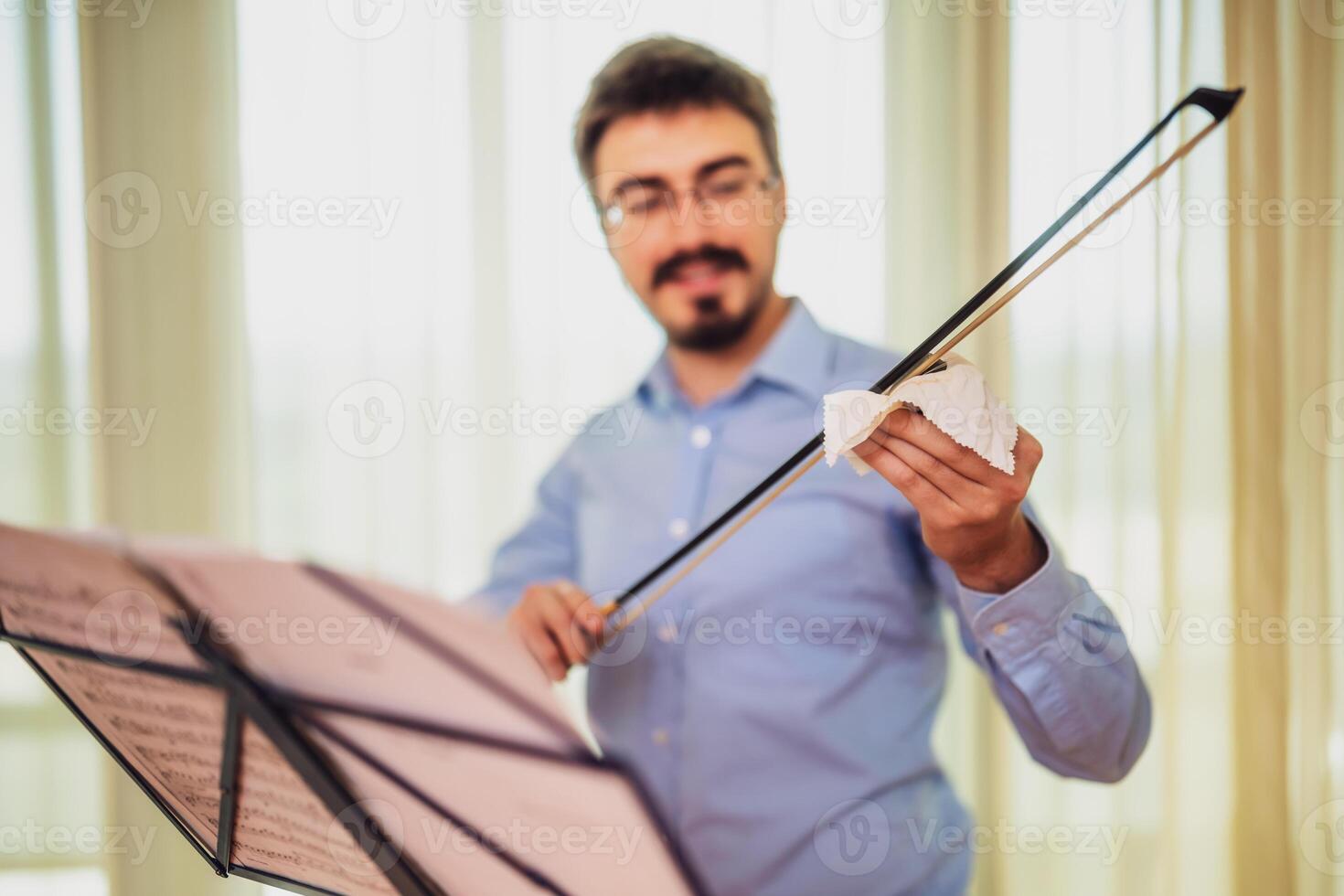 Man playing violin at home. He rosin a violin bow. photo