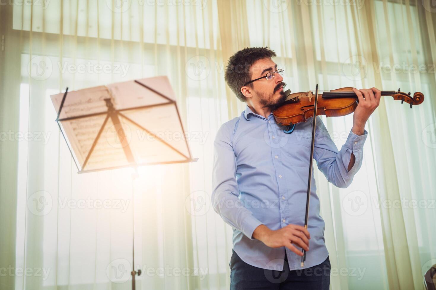 Man playing violin at home. He is cleaning his instrument. photo