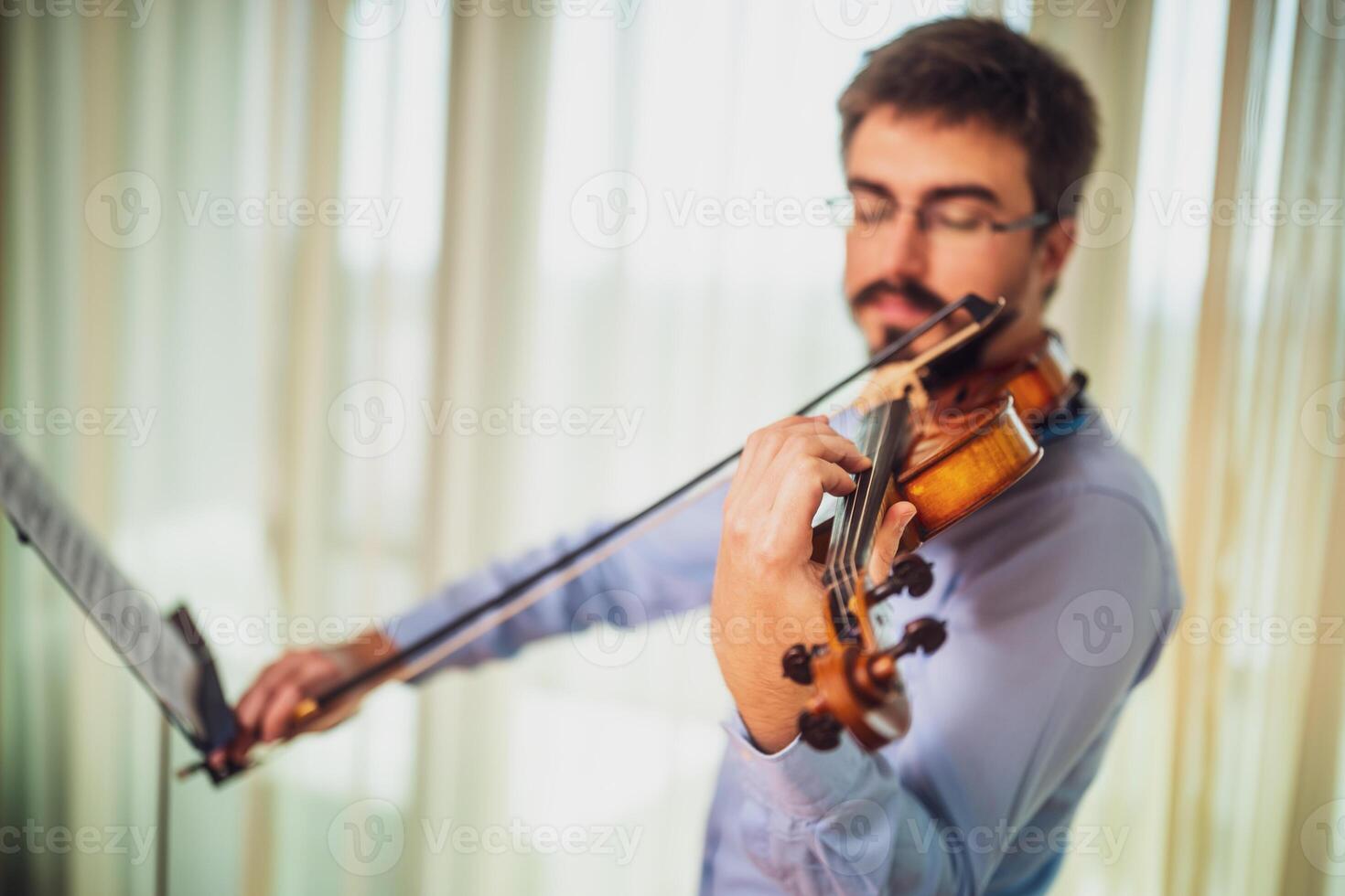 Man playing violin at home. He is cleaning his instrument. photo