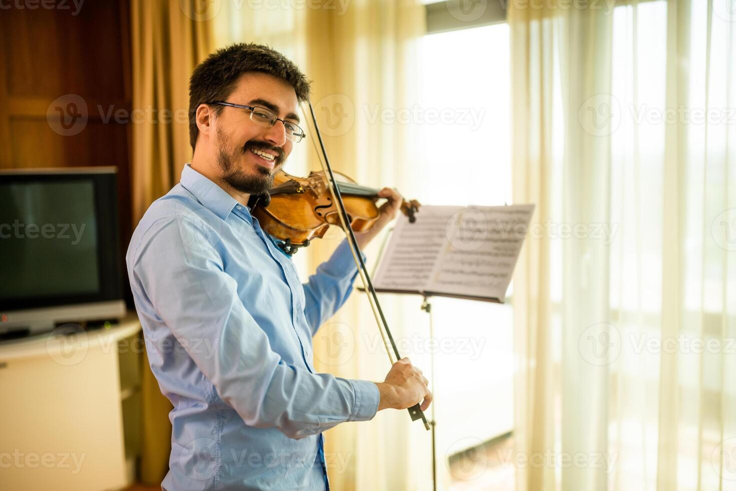 Man playing violin at home. He is cleaning his instrument. photo