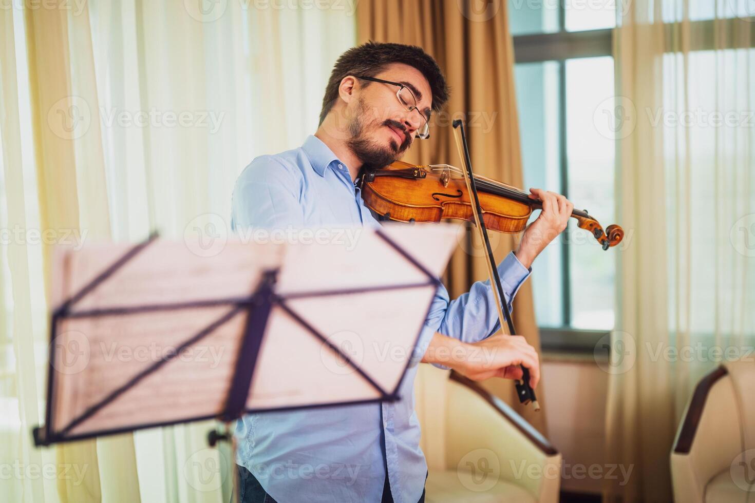 Man playing violin at home. He is cleaning his instrument. photo