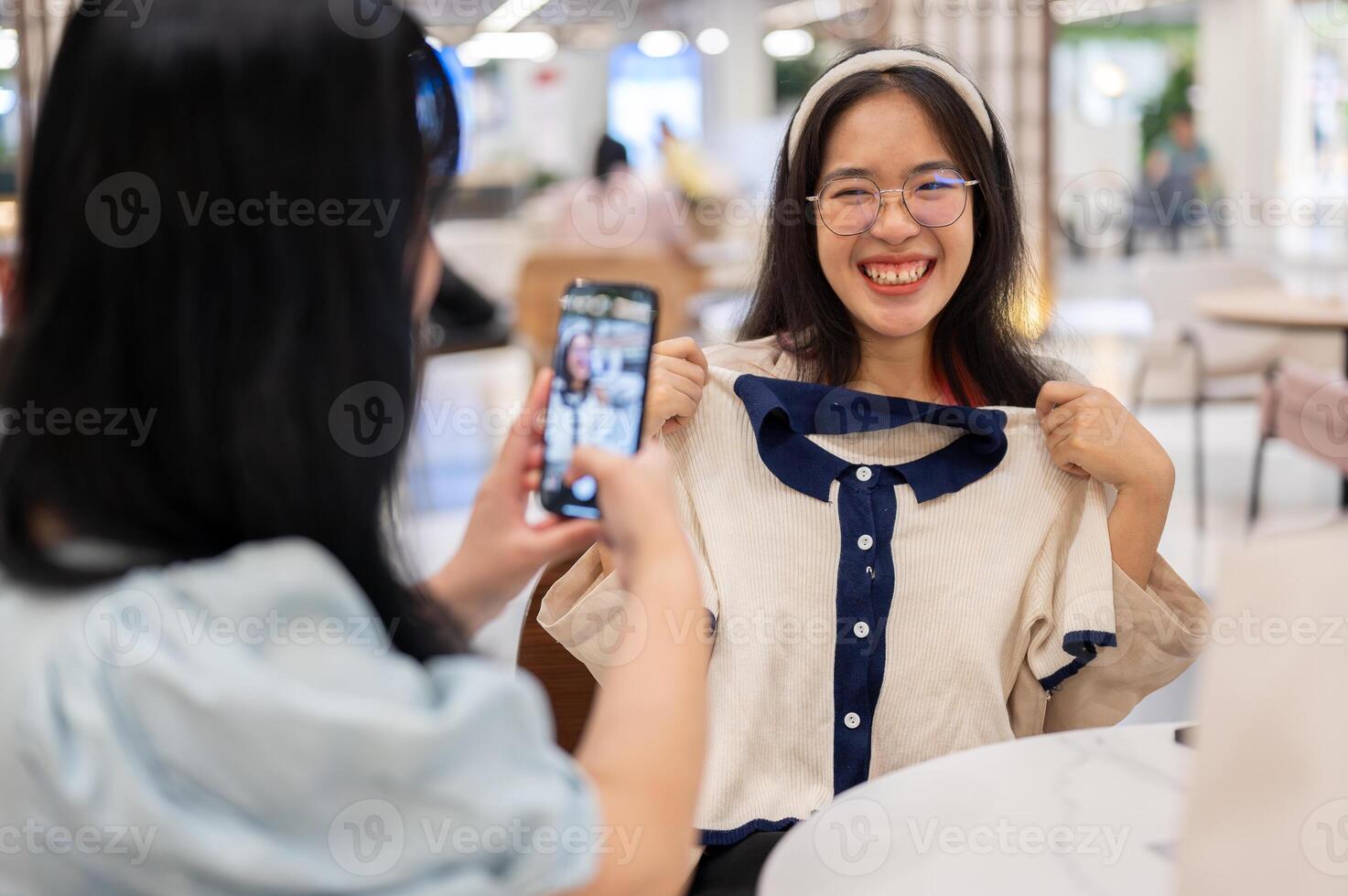 A woman taking a picture of her friend with a new clothe, having a fun shopping day together. photo