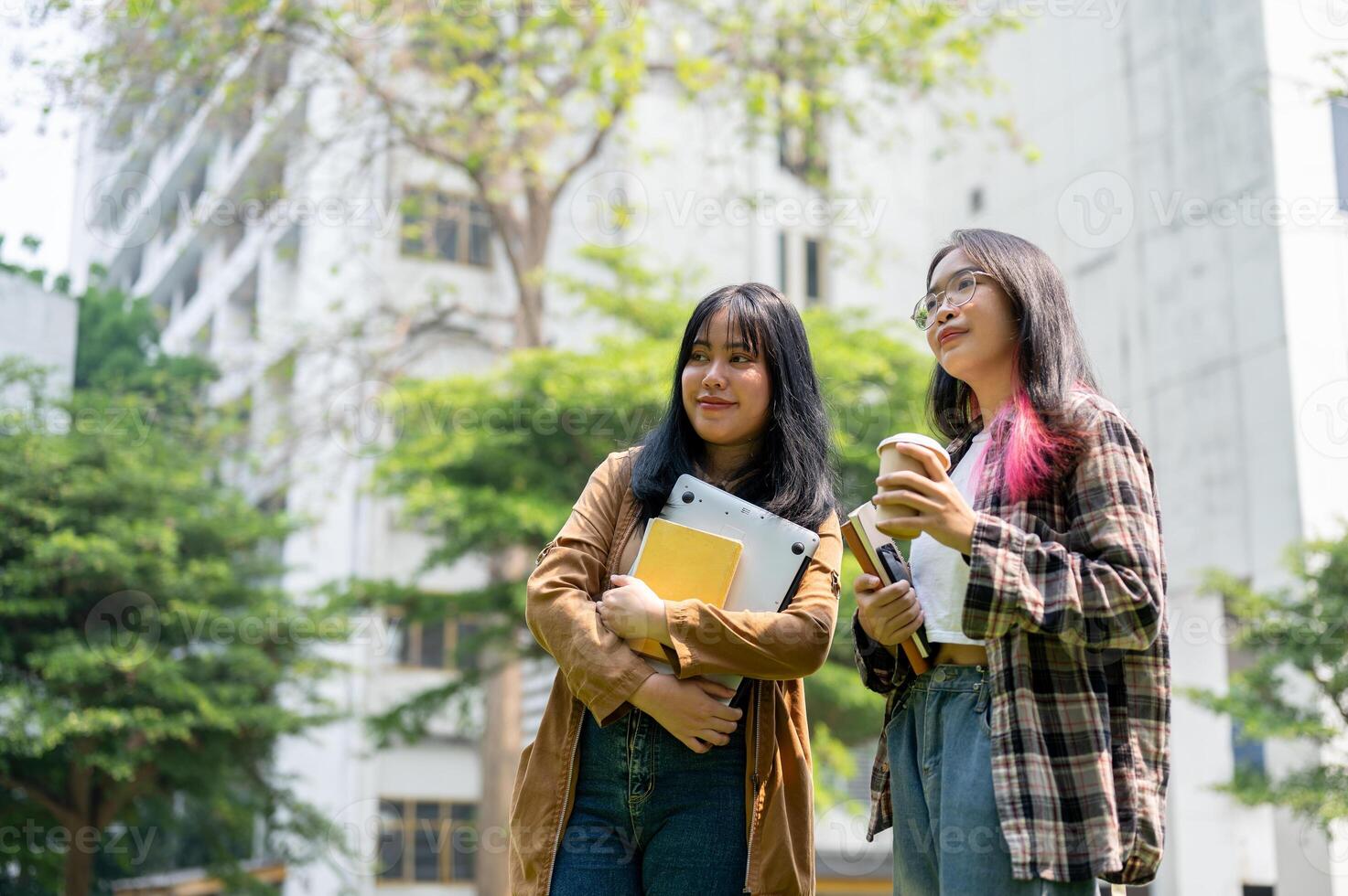 Two young Asian female college students stand together in the campus park. photo