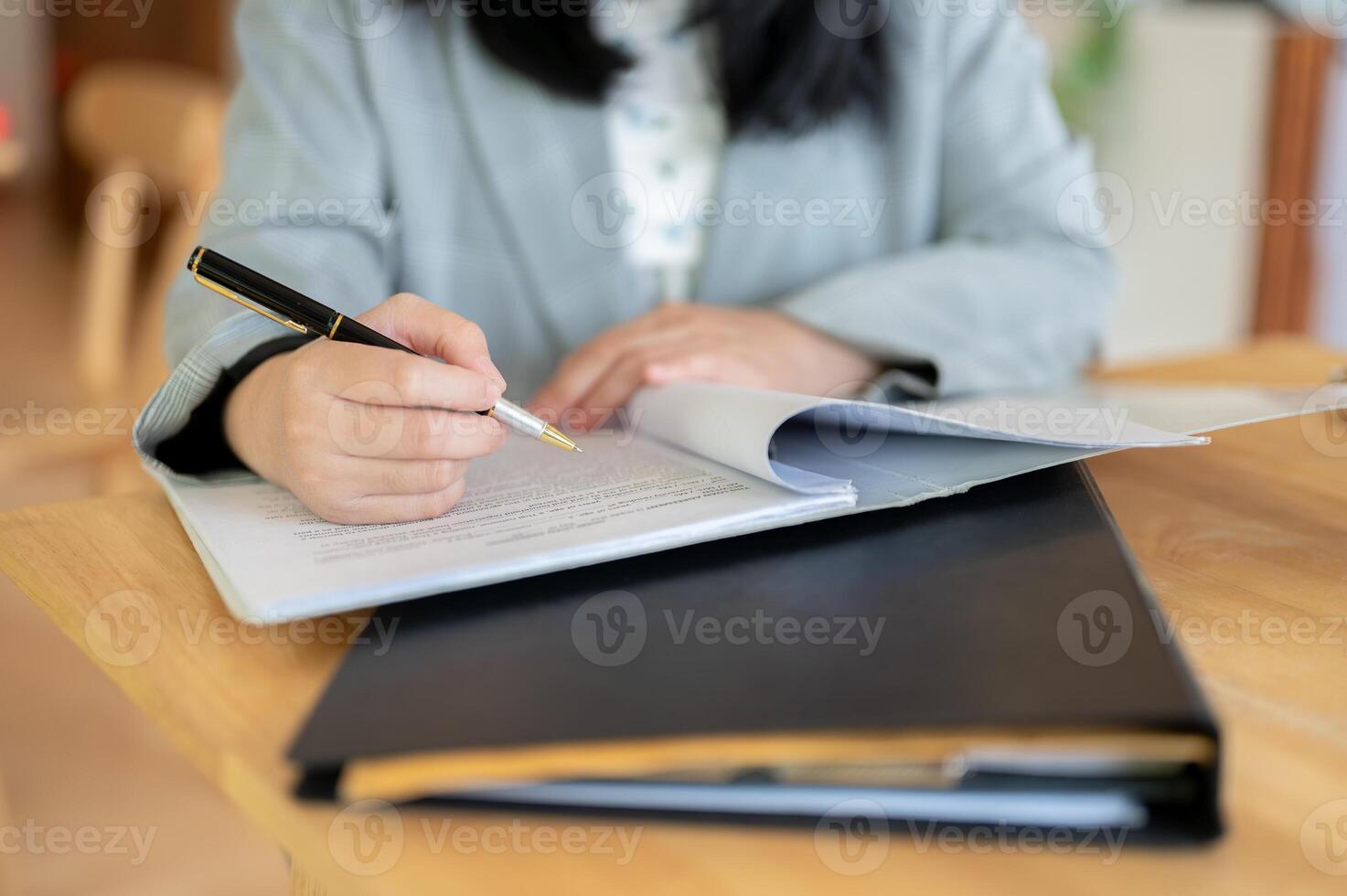 A cropped image of a businesswoman reading and signing on a document at a table. photo