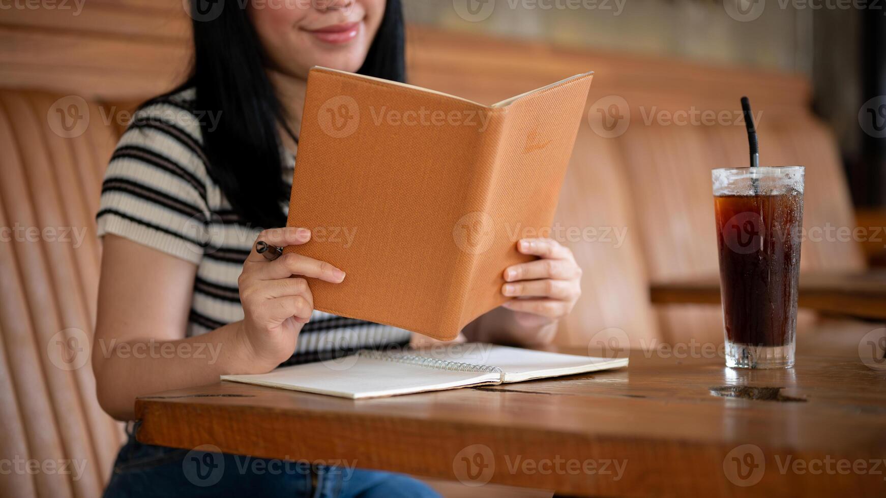 A young Asian woman is reading a book or doing homework in a beautiful vintage coffee shop. photo