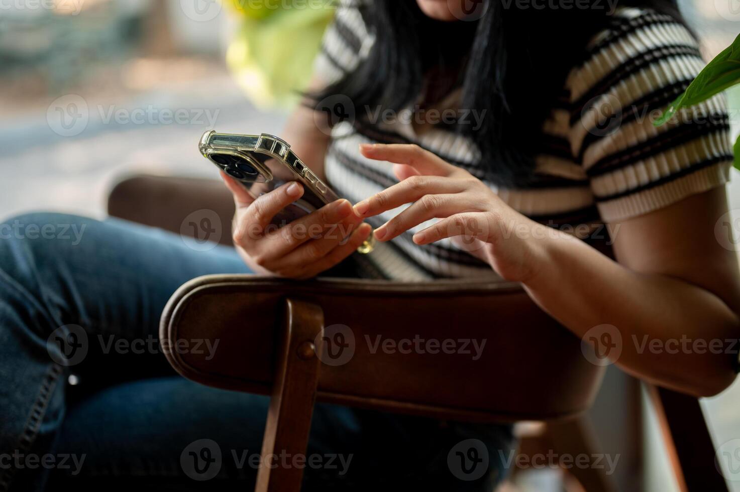 A cropped image of an Asian woman using her smartphone while relaxing in a cafe. photo