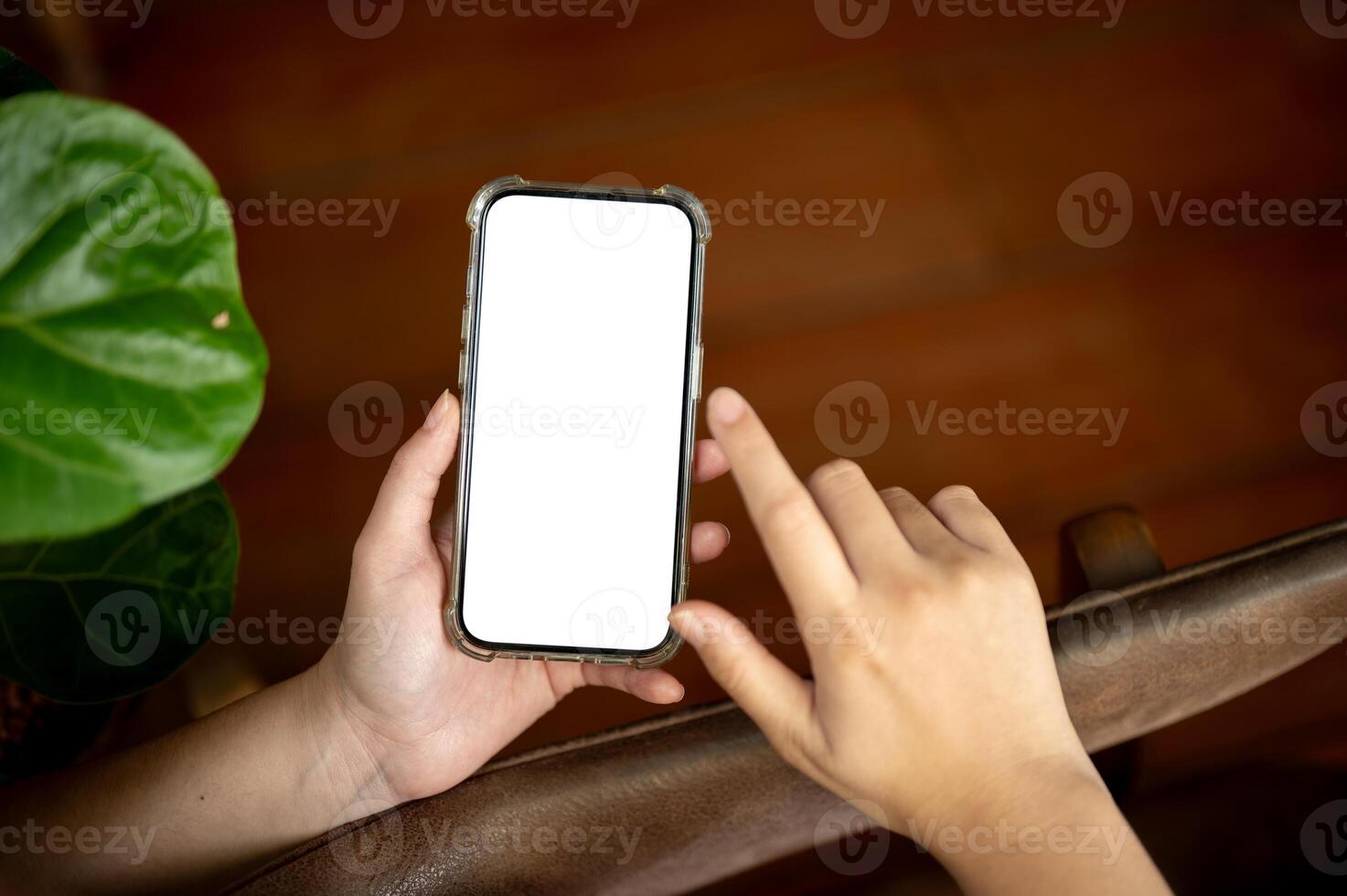 A close-up image of a woman using her smartphone indoors. A white-screen smartphone mockup photo