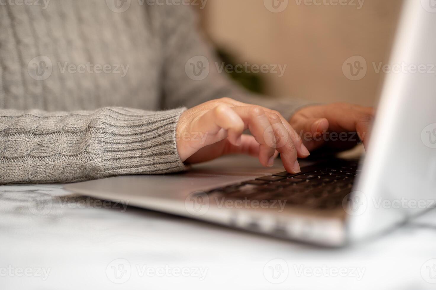 A cropped shot of a woman working on her laptop computer, typing on the laptop keyboard. photo