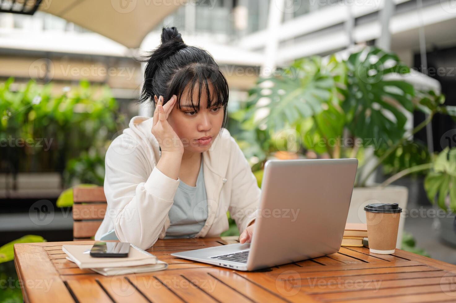 A serious, focused Asian woman is reading an online article or email on her laptop. photo