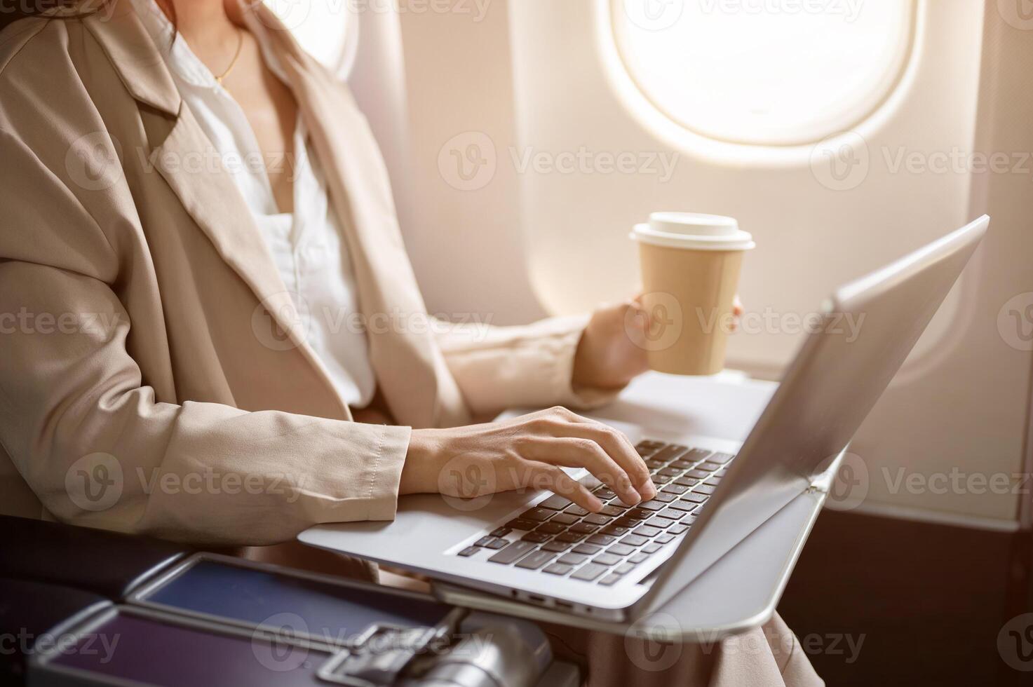 A cropped image of a hard-working businesswoman is working on her laptop during the flight. photo