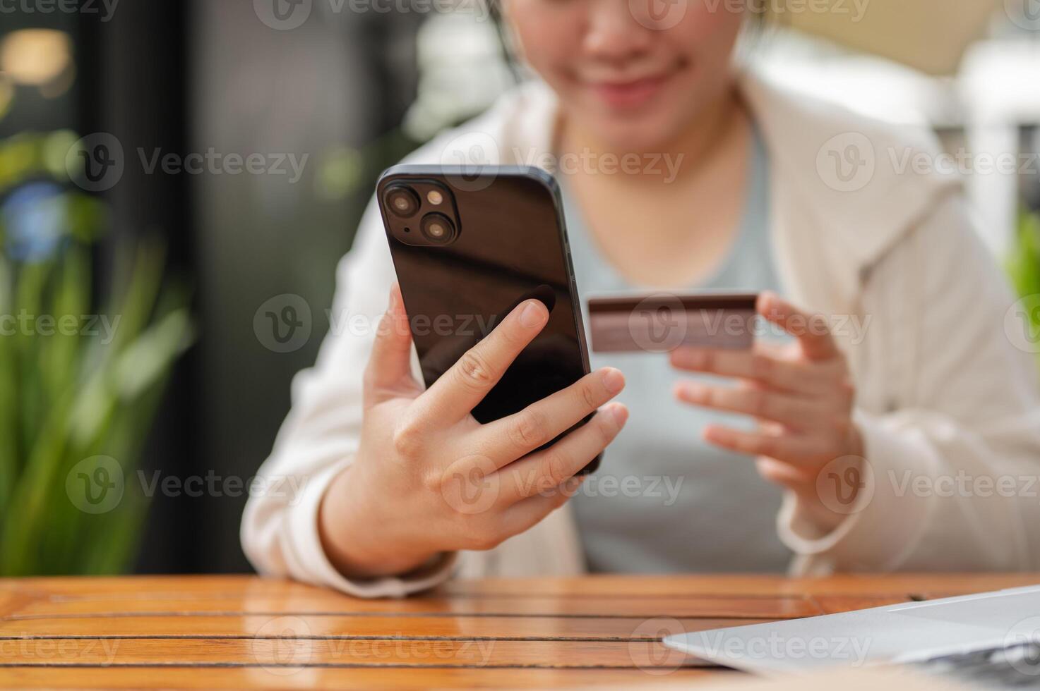 A woman sitting at an outdoor space, registering her credit card on a shopping website. photo