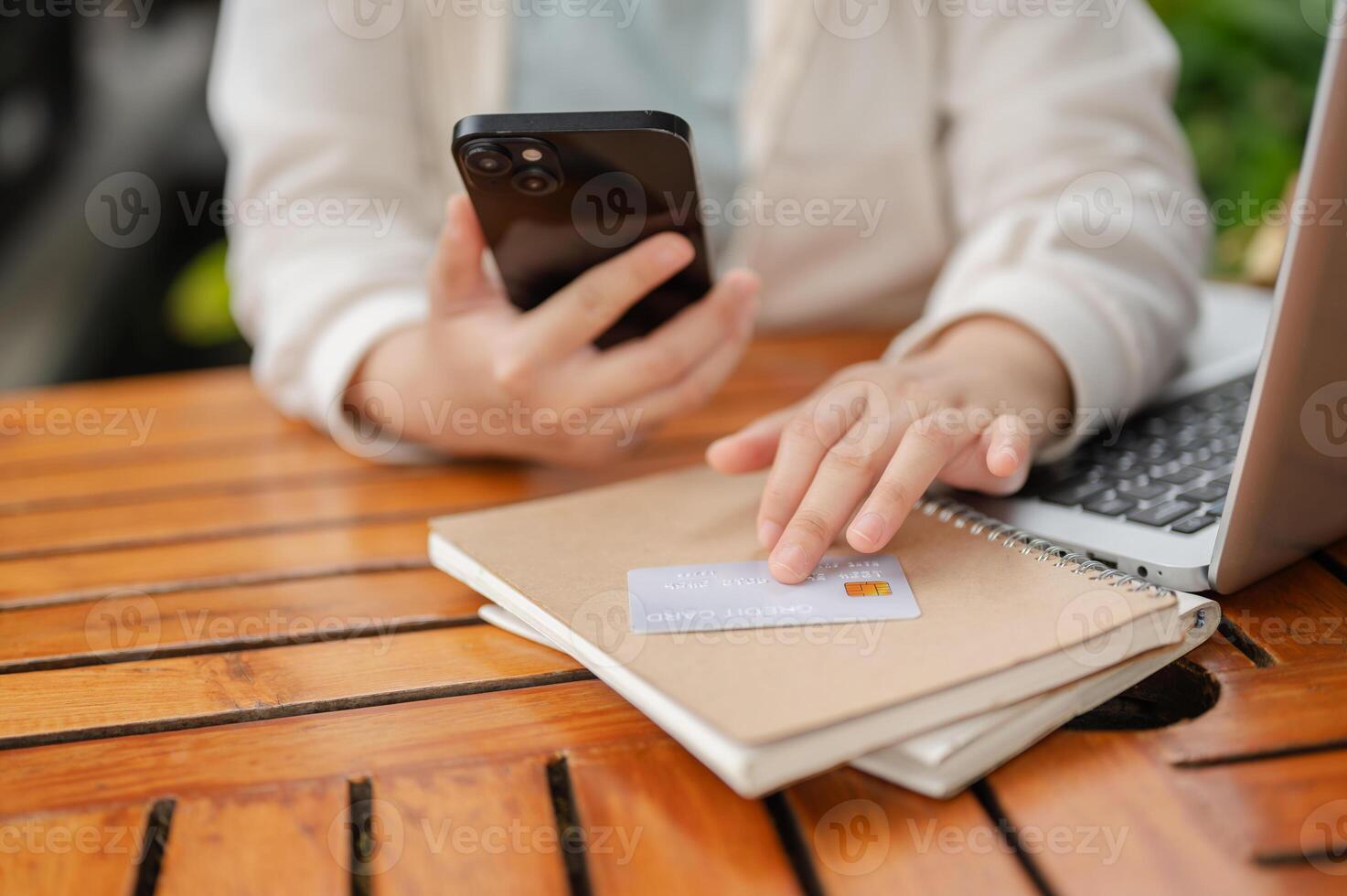 A woman sitting at an outdoor space, registering her credit card on a shopping website. photo