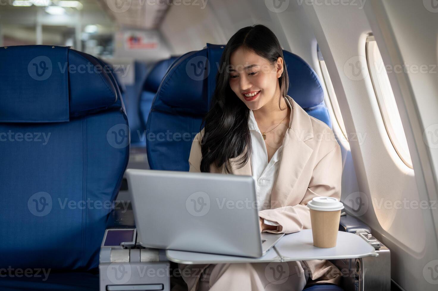 An attractive Asian female CEO is working on her laptop during the flight for her business trip. photo