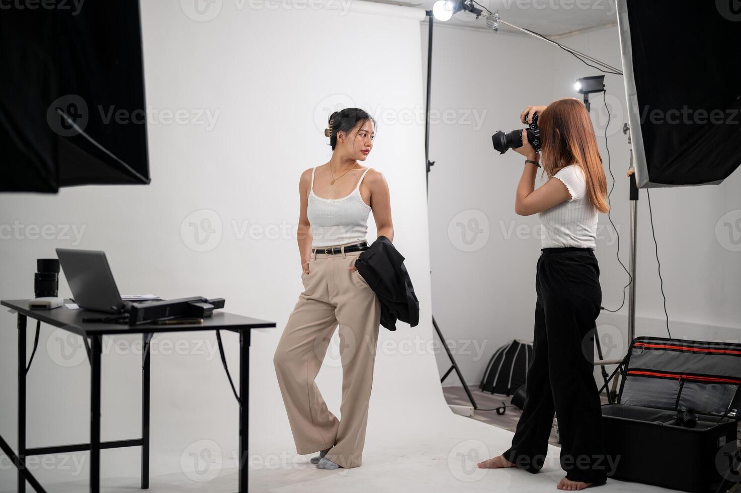 A professional photographer is taking pictures of an attractive young Asian female model in a studio photo