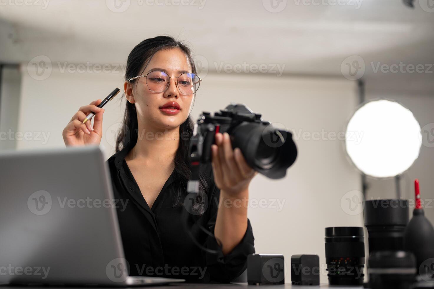 un profesional asiático hembra fotógrafo es enfoque en comprobación imágenes en su ordenador portátil. foto