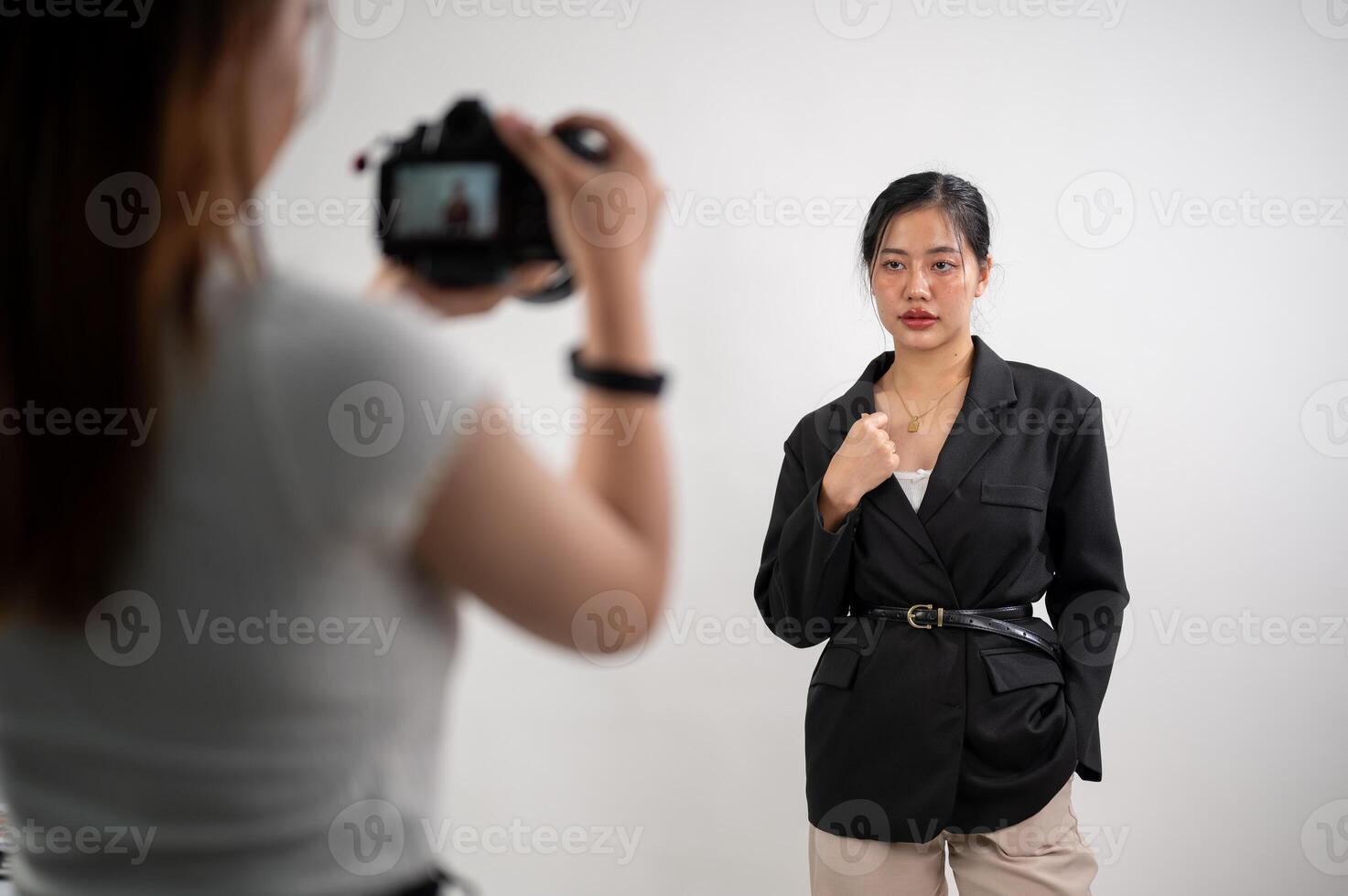 An attractive Asian female model is posing for a photographer in a modern fashion studio. photo