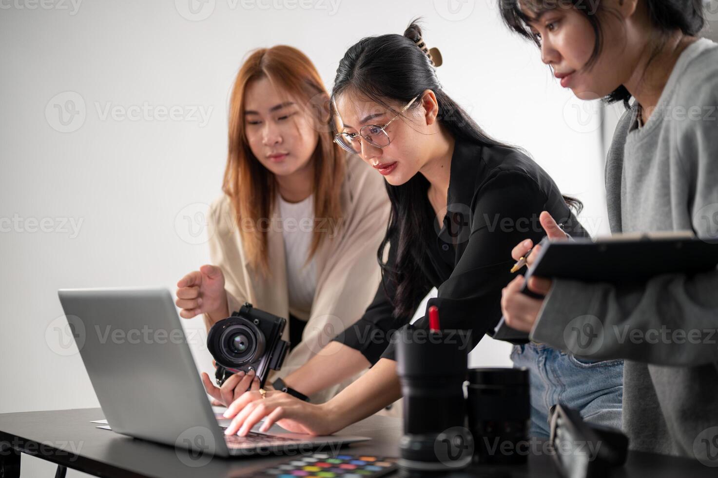 A professional Asian female photographer is working with her assistants in a photoshoot studio. photo
