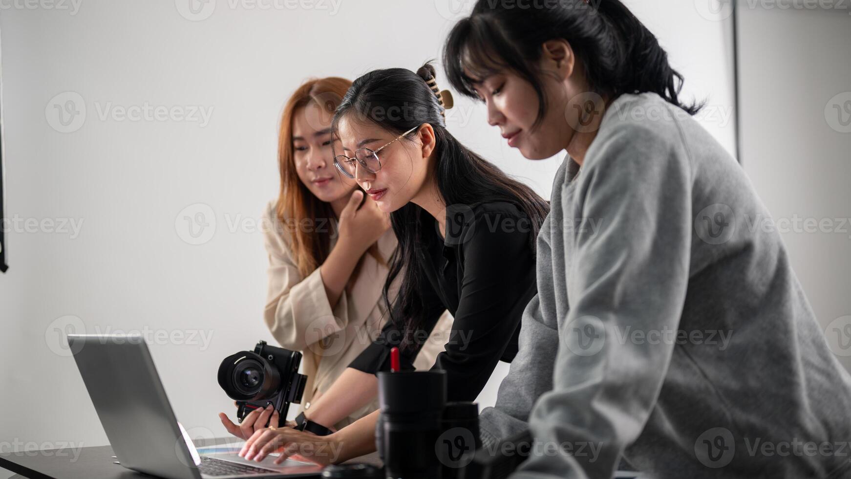 A professional Asian female photographer is working with her assistants in a photoshoot studio. photo